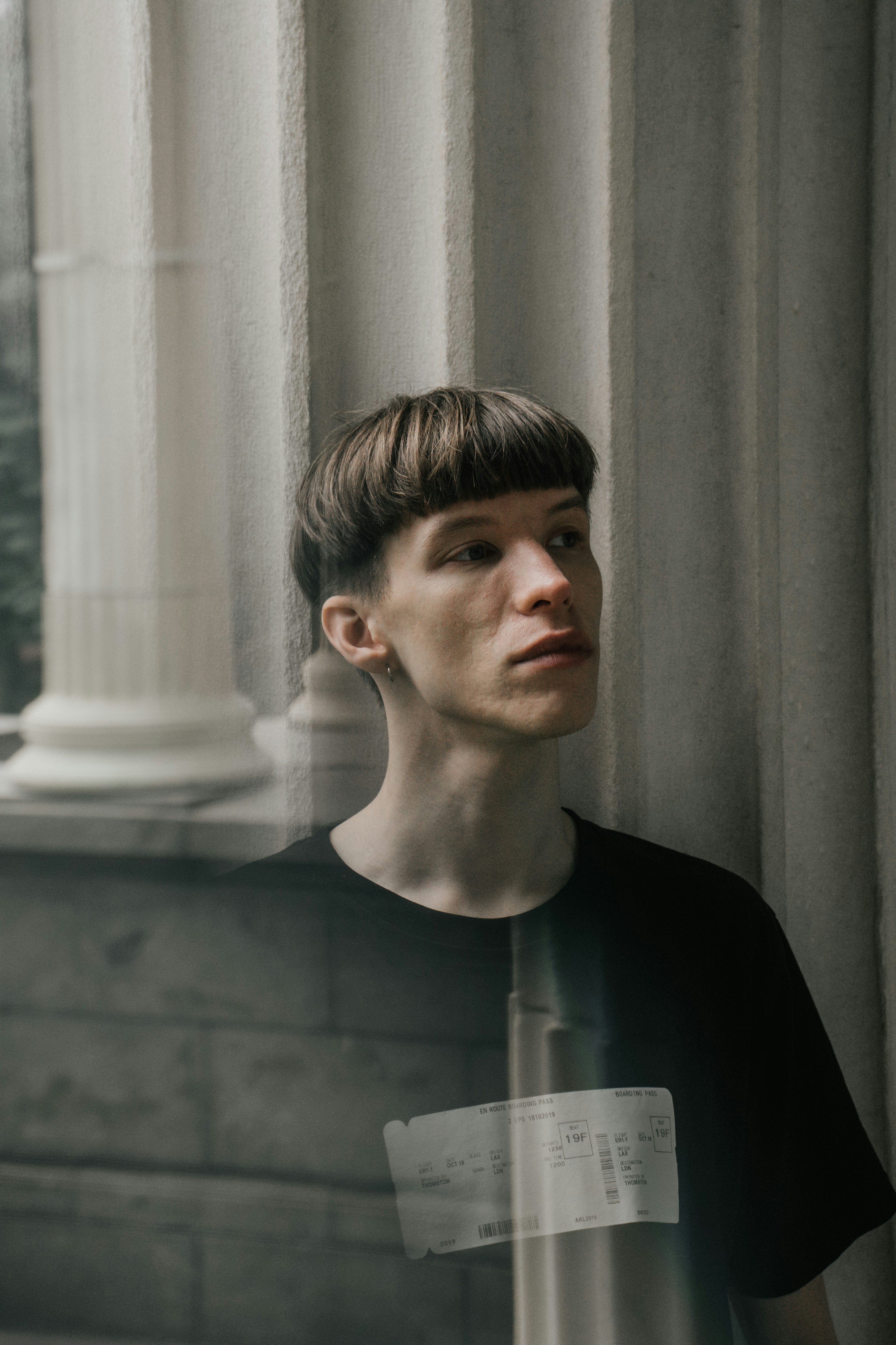 man in black crew neck shirt standing near window